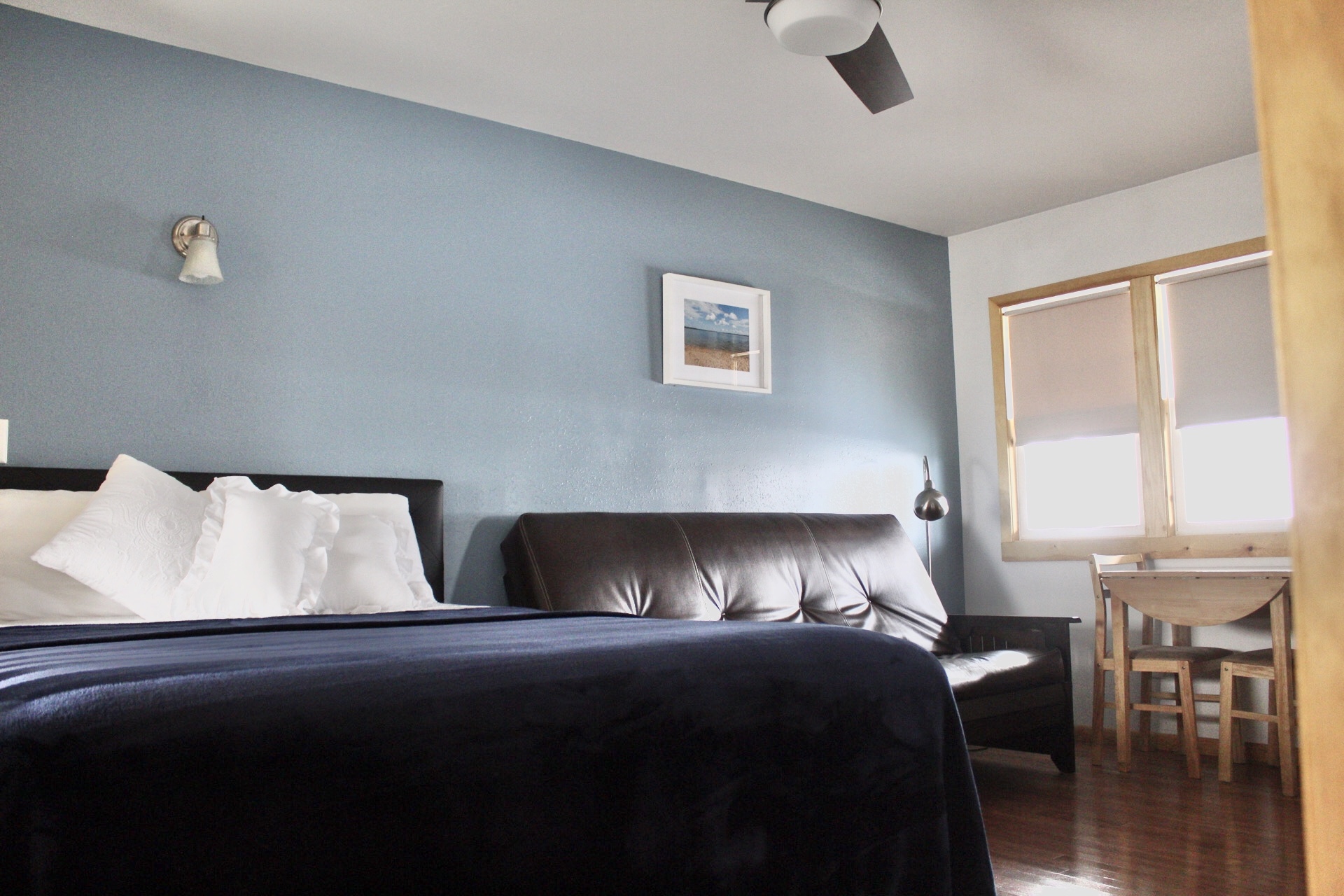 A hotel room with a bed, sofa, table, and window.