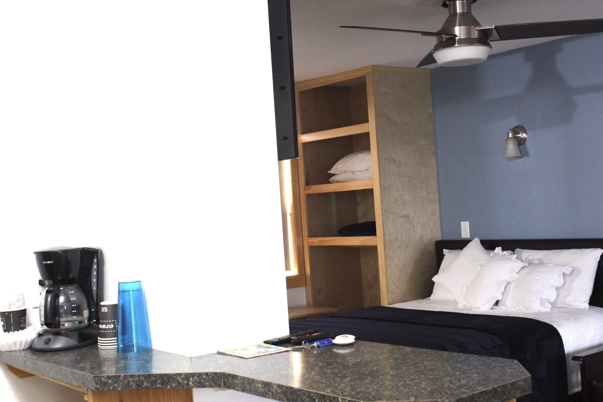 A hotel room with a bed, coffee maker, and granite countertop.