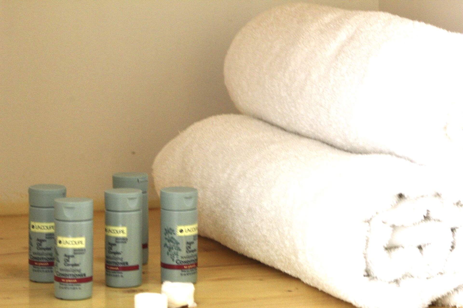 A stack of white towels and toiletries on a wooden surface.