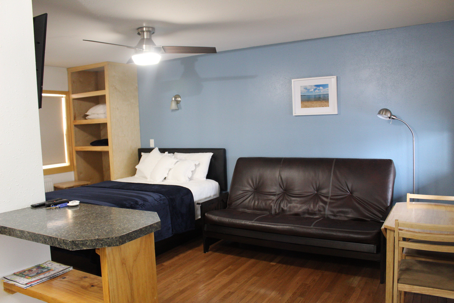 A hotel room with a bed, sofa, desk, and TV.